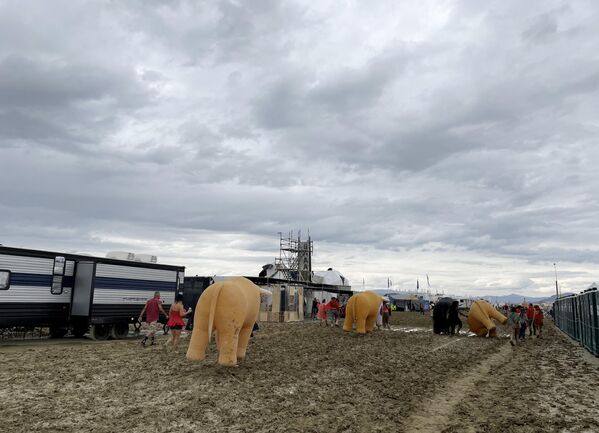 Attendees walk through a muddy desert plain on September 2, 2023, after rains turned the annual Burning Man festival site in Nevada’s Black Rock desert into a treacherous muddy quagmire. (Photo by Julie JAMMOT / AFP) - Sputnik International