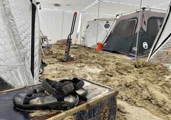 A pair of Teva sandals are seen on a chest in the middle of tents sitting in a muddy desert plain on September 3, 2023 at the site of annual Burning Man festival in Nevada’s Black Rock desert. (Photo by Julie JAMMOT / AFP) - Sputnik International