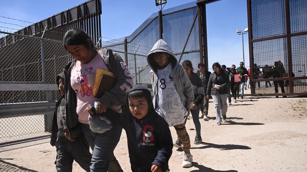 Migrants with children walk to board a bus after surrendering to US Customs and Border Protection Border Patrol agents in El Paso, Texas, on May 10, 2023. - Sputnik International