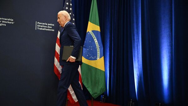 US President Joe Biden walks to the podium after bumping into the Brazilian flag - Sputnik International