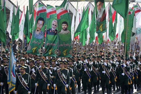 Iran&#x27;s Revolutionary Guard members march as they carry flags with portraits of the Supreme Leader Ayatollah Ali Khamenei, right, and the late military commanders. - Sputnik International