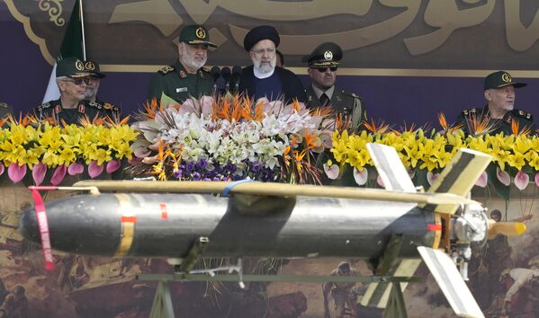 Iranian President Ebrahim Raisi, center, listens to the Revolutionary Guard Commander Gen. Hossein Salami, center left, as he reviews an annual military parade. - Sputnik International