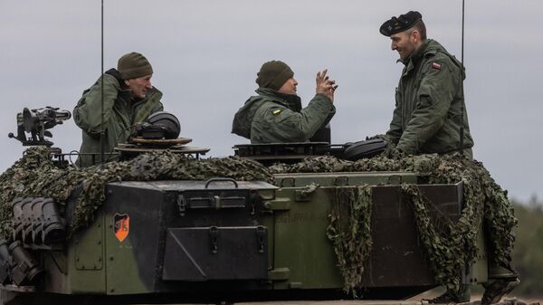 Polish and Ukrainian soldiers are seen on a Leopard 2 tank during training at the Swietoszow military base in western Poland on February 13, 2023 - Sputnik International