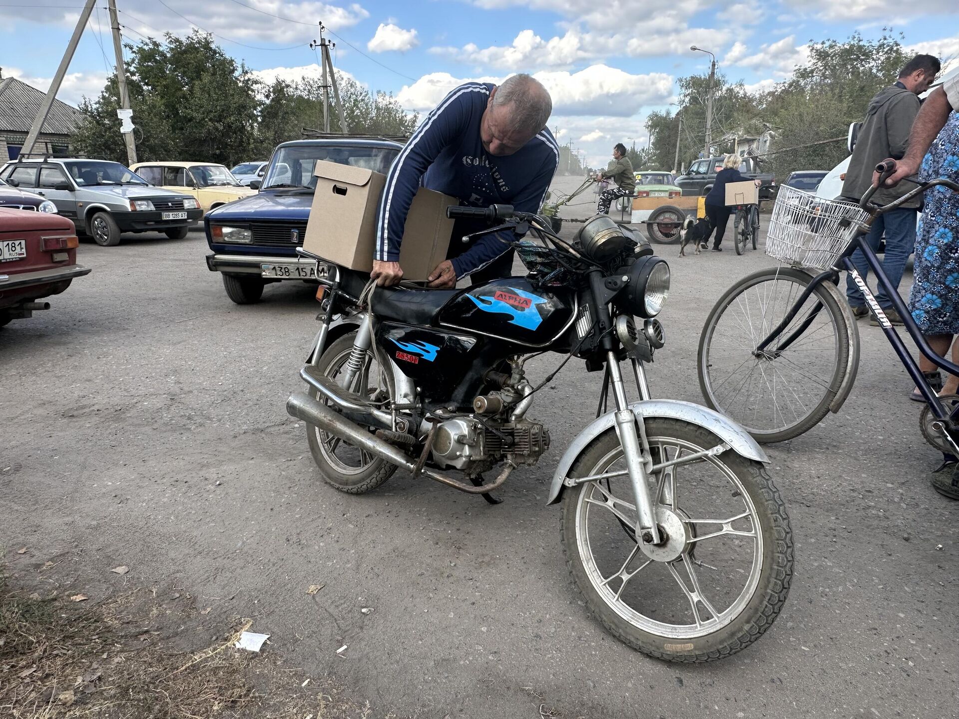 A resident of the village of Nizhneye mounts a humanitarian kit on his motorcycle - Sputnik International, 1920, 26.09.2023