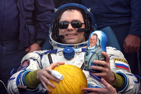 Russian cosmonaut Dmitry Petelin poses for a photo holding a muskmelon and a matryoshka doll of himself just after leaving the Soyuz MS-23 space capsule. - Sputnik International