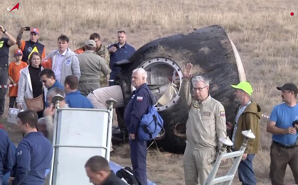 Roscosmos and NASA team members take care of the space crew brought back by the Russian Soyuz MS-23 space capsule, which lies on the ground shortly after landing. - Sputnik International