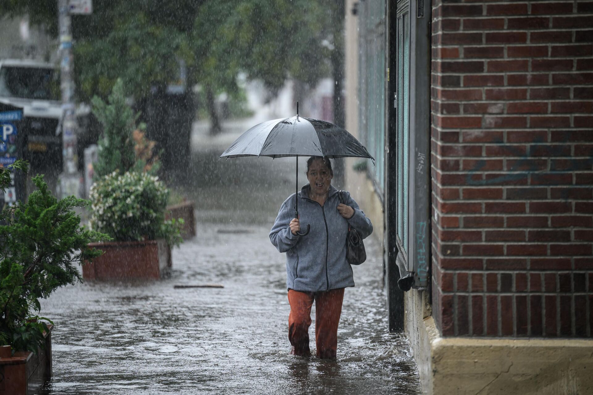 A woman holding an umbrella walks through through floodwater in Brooklyn, New York on September 29, 2023. - Sputnik International, 1920, 30.09.2023