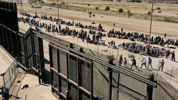 An aerial image shows migrants waiting along the border wall to surrender to US Customs and Border Protection (CBP) Border Patrol agents for immigration and asylum claim processing after crossing the Rio Grande river into the United Staes on the US-Mexico border in El Paso, Texas, on May 10, 2023. - Sputnik International