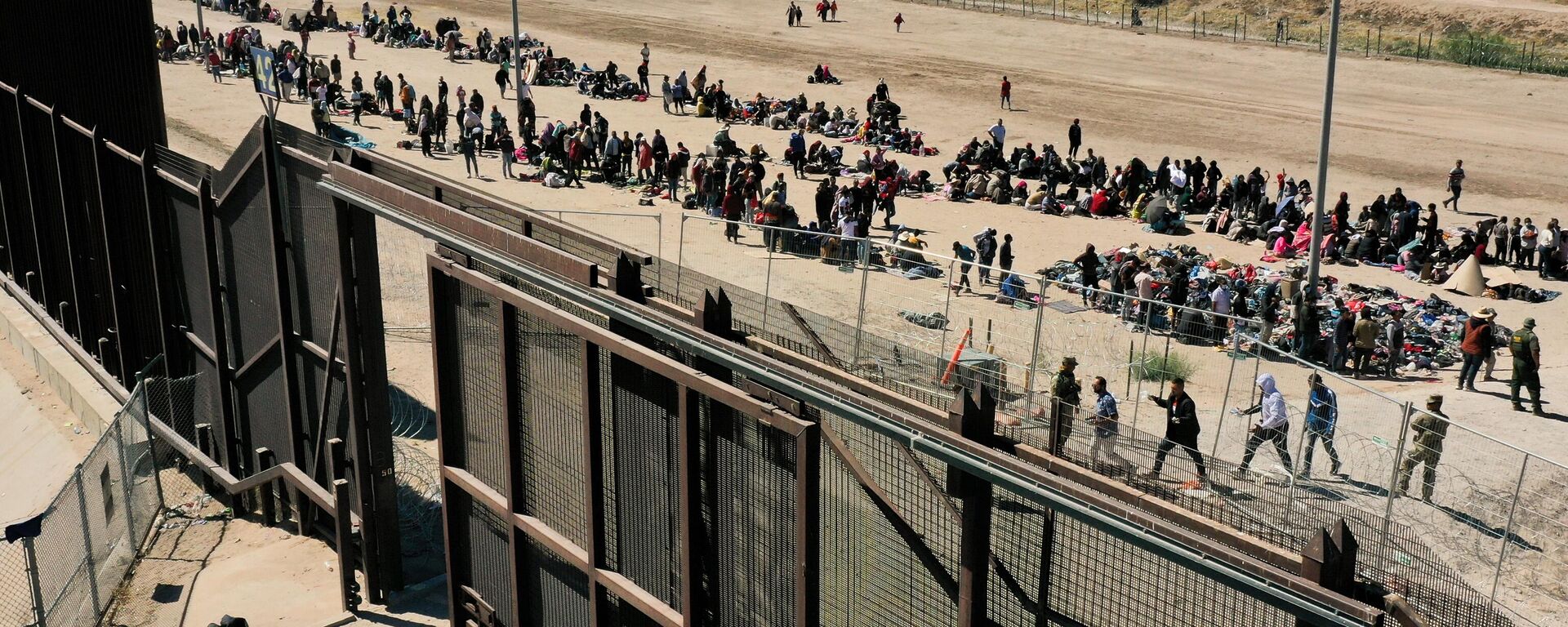 An aerial image shows migrants waiting along the border wall to surrender to US Customs and Border Protection (CBP) Border Patrol agents for immigration and asylum claim processing after crossing the Rio Grande river into the United Staes on the US-Mexico border in El Paso, Texas, on May 10, 2023. - Sputnik International, 1920, 29.10.2023