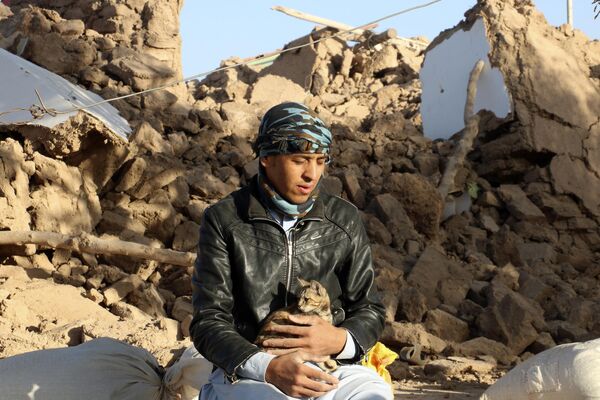 An Afghan boy holds his cat, as he sits in a courtyard of his destroyed home. - Sputnik International