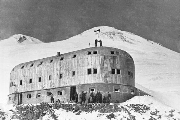 On February 13, 1943, the Red Army soldiers threw off the flags of the Third Reich and the standards of the 1st Mountain Division of the Wehrmacht &quot;Edelweiss&quot; from the western peak of Mount Elbrus, installing instead the Soviet banners with a hammer and sickle. Soldiers installing the USSR flag at the Priyut II (lit. Shelter II) station on the Mount Elbrus. - Sputnik International