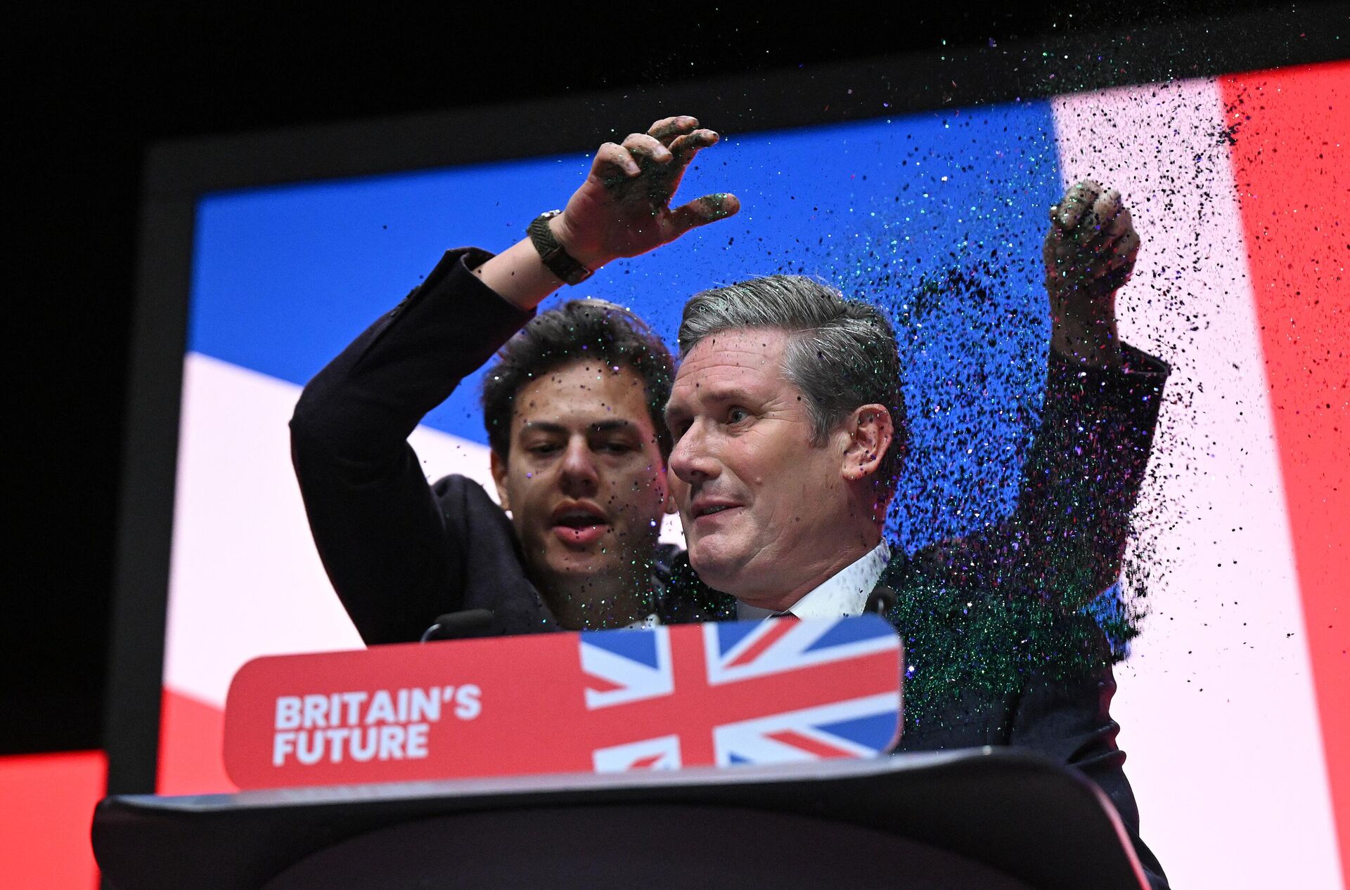 A protester throws glitter on Britain's main opposition Labour Party leader Keir Starmer (R) at the start of his keynote address to delegates on the third day of the annual Labour Party conference in Liverpool, northwest England, on October 10, 2023. - Sputnik International, 1920, 10.10.2023