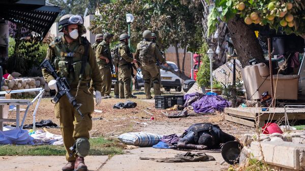 Israeli soldiers stand near the body of a Palestinian militant in Kfar Aza, in the south of Israel, bordering Gaza Strip on October 10, 2023.  - Sputnik International