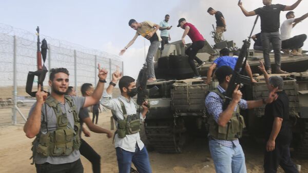 Palestinian militants celebrate by an Israeli tank at the border fence of the Gaza Strip - Sputnik International