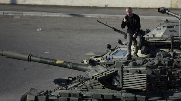 A man poses for pictures on a captured Ukrainian tank in Lugansk - Sputnik International