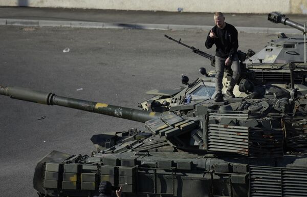 A visitor poses for pictures on top of a captured Ukrainian tank. - Sputnik International