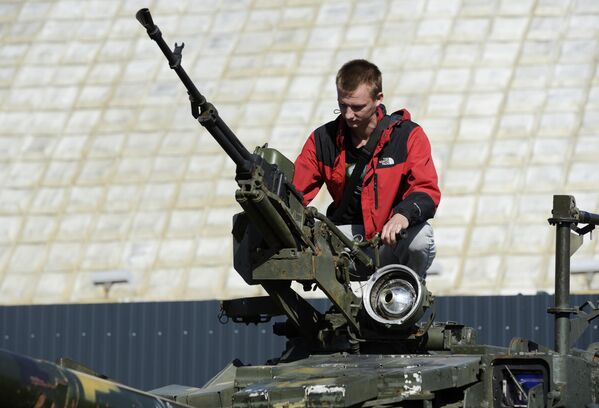 A visitor examines a gun on top of a captured Ukrainian tank. - Sputnik International