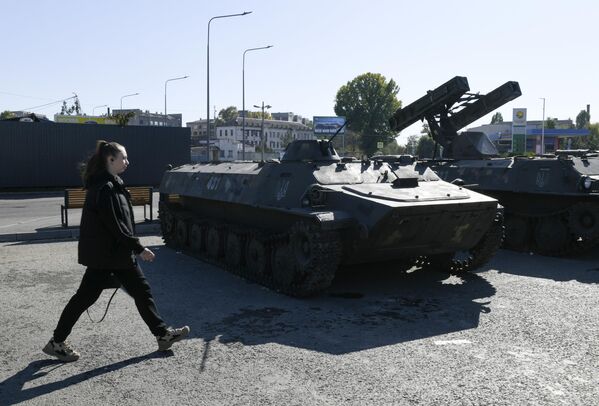 A visitor walks past captured Ukrainian armored vehicles. - Sputnik International