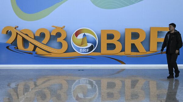 A man walks past the logo of the Belt and Road Forum at the National Convention Center in Beijing on October 15, 2023. - Sputnik International