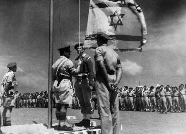 A picture released on June 8, 1948 shows an Israeli officer raising the National Flag for the first time during the celebration of the birth of the Israeli State after its proclamation, on May 14, 1948. - Sputnik International