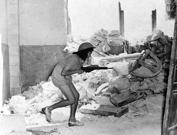 An Israeli soldier, armed with a sten gun, picks her way through the shattered walls of Sulimans Way, in the old city of Jerusalem, Palestine, July 20, 1948, which forms a front line between the Arabs inside and Jewish forces outside the walls. Fierce fighting happened between the two forces following the expiry of a two-day truce. - Sputnik International