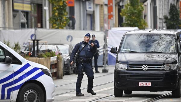 A police officer gestures as he stands guard in front of the house in the Schaerbeek area of Brussels on October 17, 2023, where the suspected perpetrator of the attack in Brussels was shot dead during a police intervention - Sputnik International