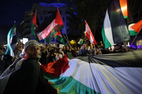 Protestors hold a Palestinian flag during a rally in support of Palestinians in Barcelona. - Sputnik International
