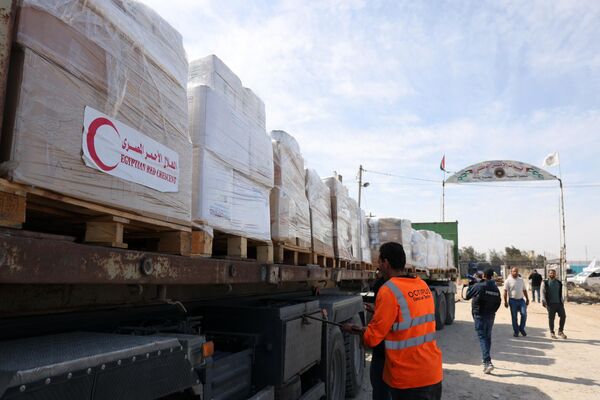 People gather around the first of 20 trucks carrying humanitarian aid that entered the Gaza Strip from Egypt via the Rafah border crossing on 21 October 2023.  - Sputnik International