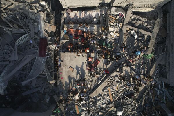 Palestinians inspect the rubble of buildings hit by an Israeli airstrike in the Al Shati refugee camp on October 12, 2023. - Sputnik International