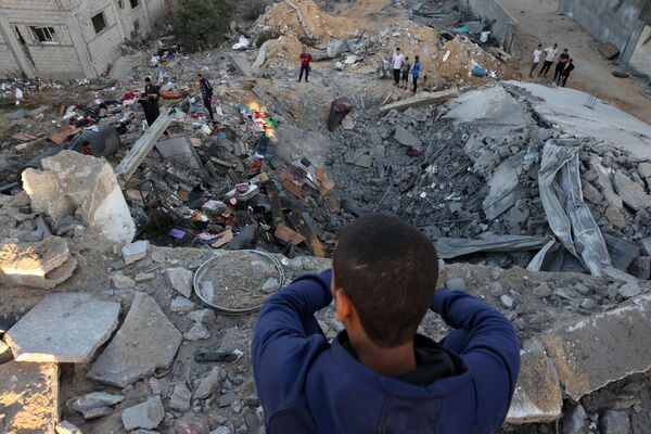 A young boy looks on as people check the rubble of a building destroyed by an Israeli bombardment in Rafah in the southern Gaza Strip on October 21, 2023. - Sputnik International