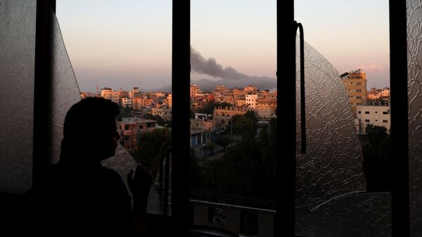 A Palestinian child watches as smoke billows on the horizon after an Israeli air strike in Gaza City on October 13, 2023. - Sputnik International