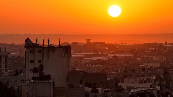 The sun rises behind a damaged building over the skyline of Khan Yunis in the southern Gaza Strip on October 19, 2023. - Sputnik International