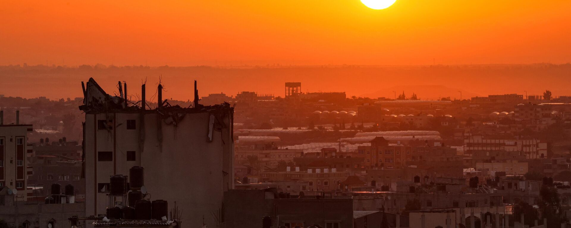 The sun rises behind a damaged building over the skyline of Khan Yunis in the southern Gaza Strip on October 19, 2023. - Sputnik International, 1920, 27.10.2023