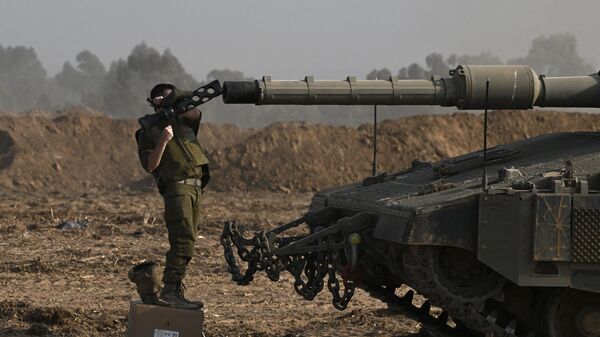 An Israeli solider checks the gun of a Merkava tank deployed along Israel's border with Gaza on October 24, 2023, amid the ongoing battles between Israel and the Palestinian militant group, Hamas. - Sputnik International
