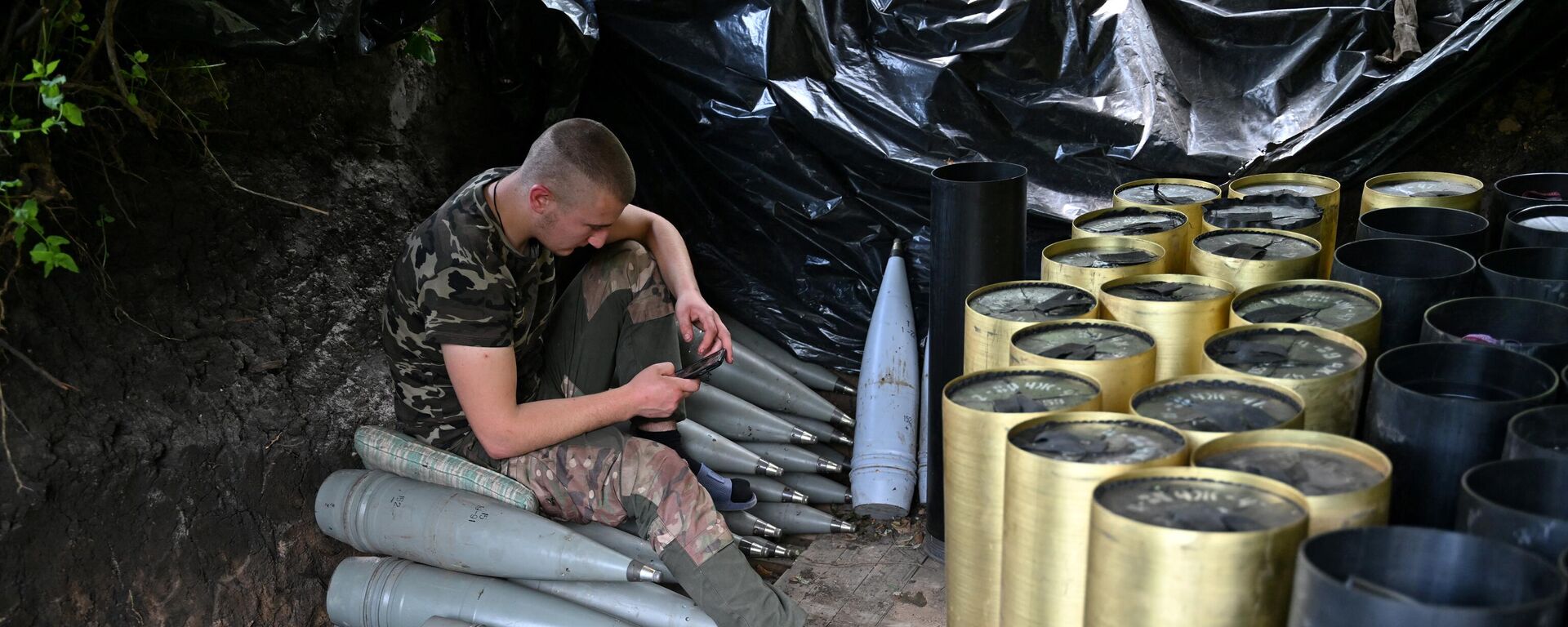 A Ukrainian artilleryman checks his mobile phone next to shells and the cases of propellant charges as he gets a rest at a position near Avdeyevka in the Donetsk region on June 23, 2023. - Sputnik International, 1920, 24.11.2023