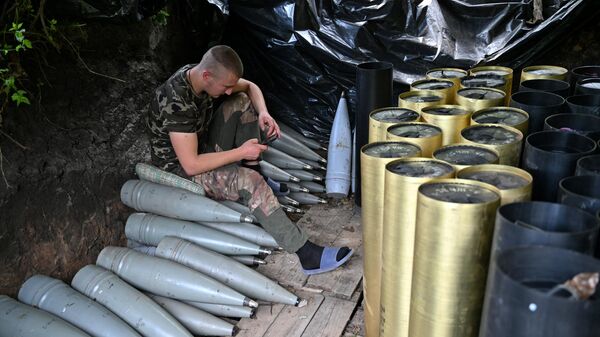 A Ukrainian artilleryman checks his mobile phone next to shells and the cases of propellant charges as he gets a rest at a position near Avdeyevka in the Donetsk region on June 23, 2023. - Sputnik International