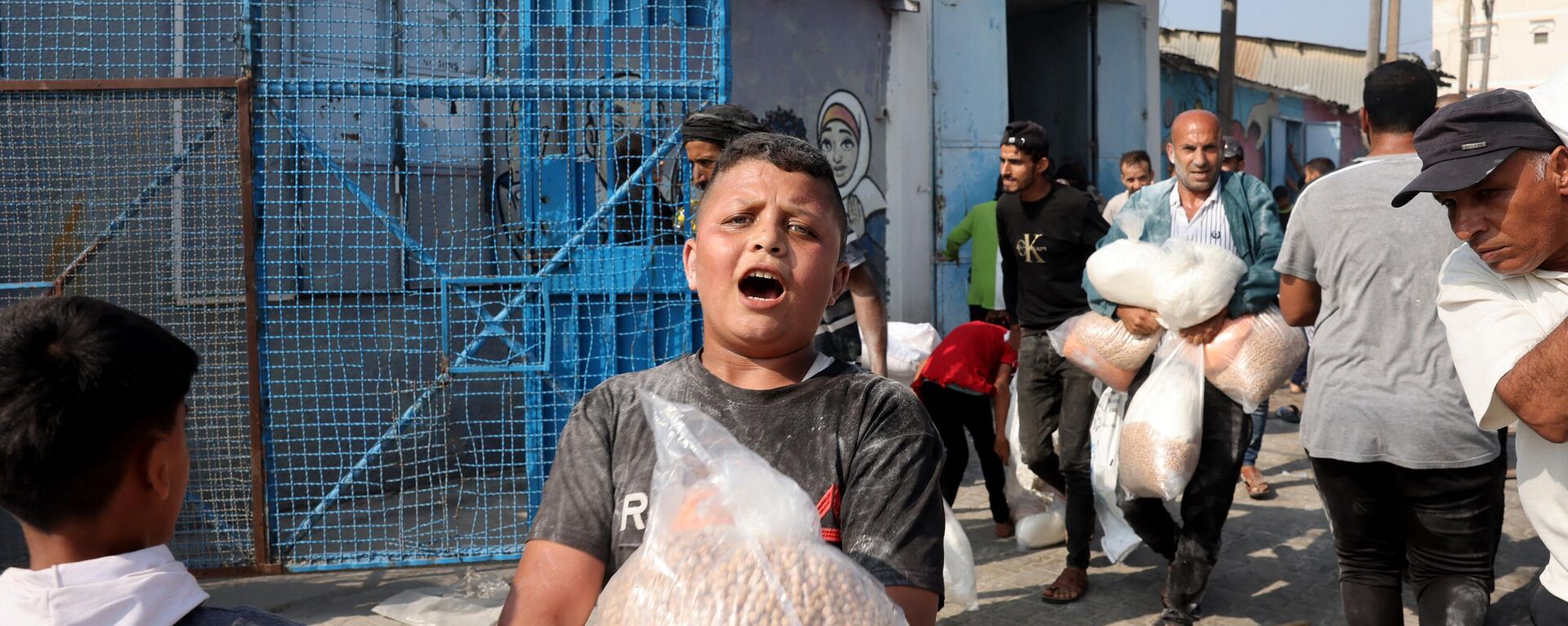 A Palestinian boy holds a bag of chickpeas received at the UN humanitarian center in Deir el-Balah. - Sputnik International, 1920, 29.10.2023