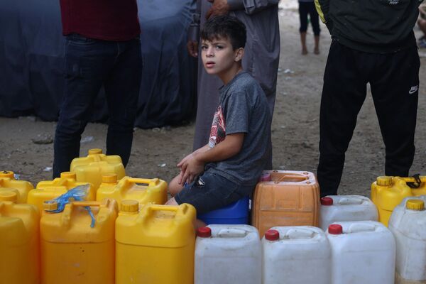 A young Palestinian sits on plastic jerrycans at a water filling point, in Rafah in the southern Gaza Strip, amid the ongoing battles between Israel and the Palestinian group Hamas. Thousands of civilians, both Palestinians and Israelis, have died since October 7, after Palestinian Hamas militants entered southern Israel in an unprecedented attack, triggering a war declared by Israel on Hamas with retaliatory bombings on Gaza. - Sputnik International