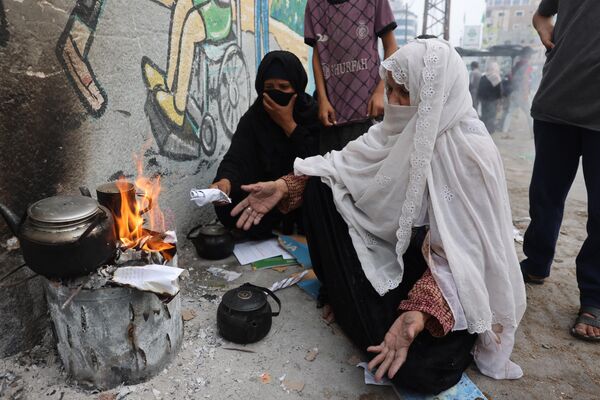 Women burn paper to heat water for tea in Rafah in the southern Gaza Strip.  - Sputnik International