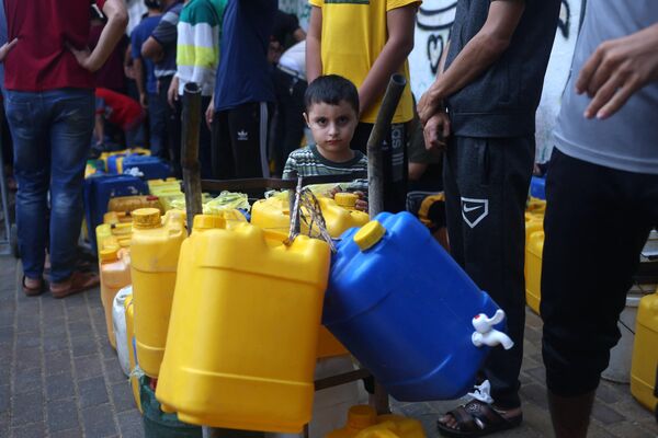 A young Palestinian waits near plastic jerrycans as people queue at a water filling point in Rafah in the southern Gaza Strip amid the ongoing battles between Israel and the Palestinian group Hamas.  - Sputnik International