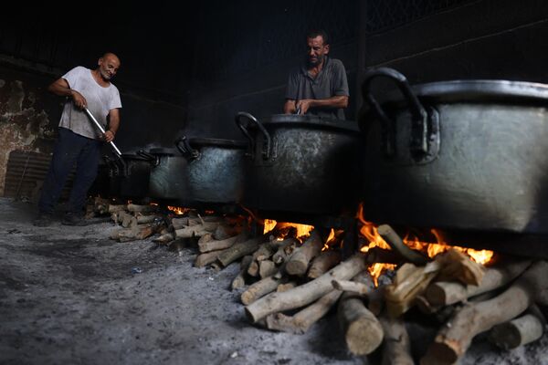 Palestinian men prepare food in large pots on bonfires due to the gas shortage. - Sputnik International