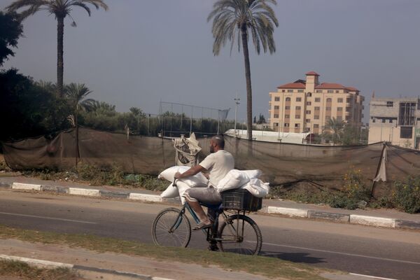 A Palestinian cyclist with bags of flour in Deir al-Balah on October 28, amid the ongoing food crisis in the Gaza Strip. - Sputnik International