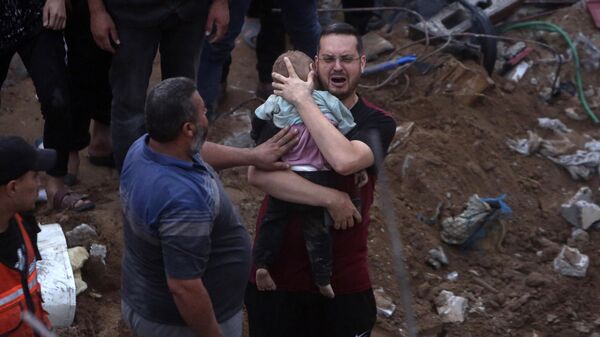 A Palestinian man cries while holding a dead child who was found under the rubble of a destroyed building following Israeli airstrikes in Nusseirat refugee camp, central Gaza Strip, Tuesday, Oct. 31, 2023 - Sputnik International