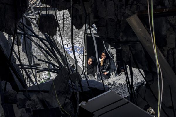 Two women peer out of a destroyed building&#x27;s window in Rafah, located in the southern Gaza Strip, looking at the destructive aftermath of Israel&#x27;s heavy bombardment. - Sputnik International