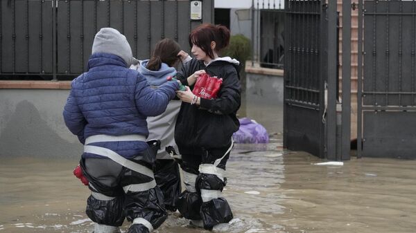 People make thier way on a flooded street in Campi di Bisenzio, in the central Italian Tuscany region, Friday, Nov. 3, 2023.  - Sputnik International