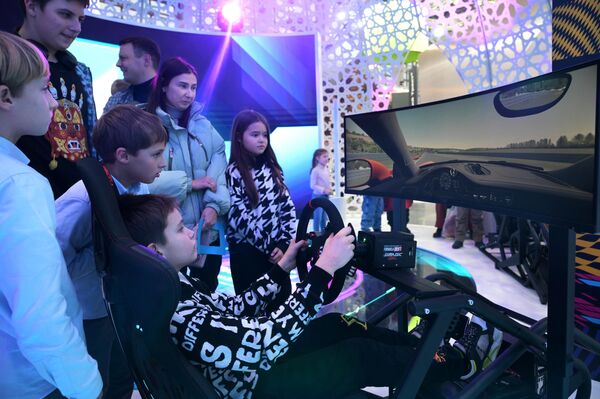 Young visitor of the RUSSIA EXPO is trying a driving simulator - Sputnik International
