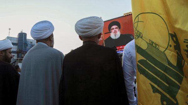 Iraqi demonstrators watch a speech from Lebanon's militant Hezbollah leader Sayyed Hassan Nasrallah on a screen as they hold flags of, Hezbollah during a pro-Palestinian rally in Basra, Iraq, Friday, Nov. 3, 2023.  - Sputnik International