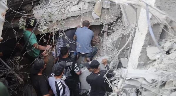 Locals clear rubble in search of survivors after an Israeli strike on a residential building. - Sputnik International