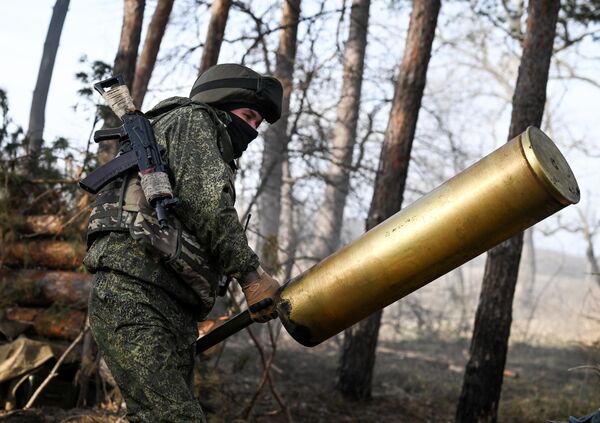 Russian trooper carries a massive empty shell casing from the Giatsint-B artillery piece after fire. - Sputnik International