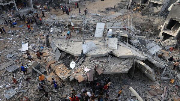 This aerial picture shows people gathered around a destroyed building following Israeli bombing on Rafah in the southern Gaza Strip, on November 11, 2023. - Sputnik International